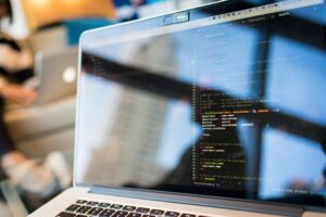 Home 7 Laptop displaying code with reflection, perfect for tech and programming themes.