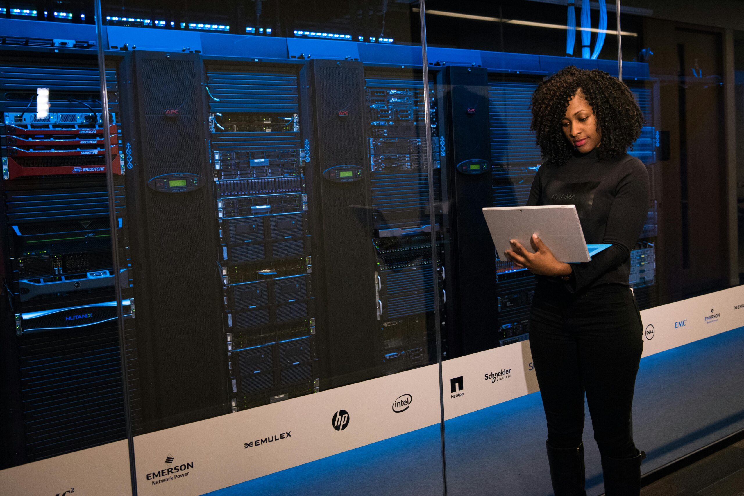 Services 5 A female engineer using a laptop while monitoring data servers in a modern server room.