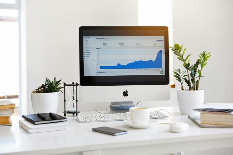 About 1 A clean, contemporary workspace featuring a desktop with analytics on the screen and plants for a fresh look.