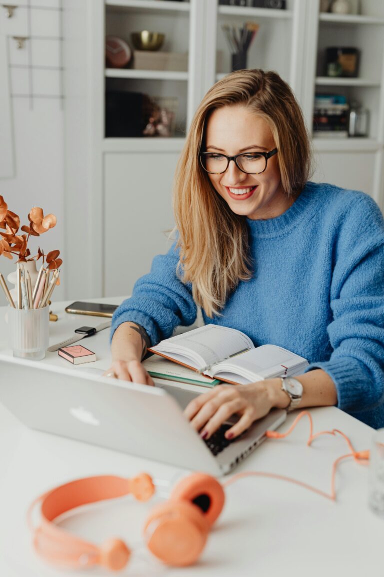 Computer Upgrades 2 A cheerful woman in a blue sweater working remotely with a laptop in a cozy home setting.