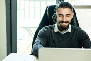 Home 3 A friendly customer support agent wearing headphones, working in an office environment.