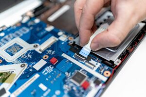 Home 2 Close-up image of hands repairing a laptop circuit board showing intricate details of electronics.