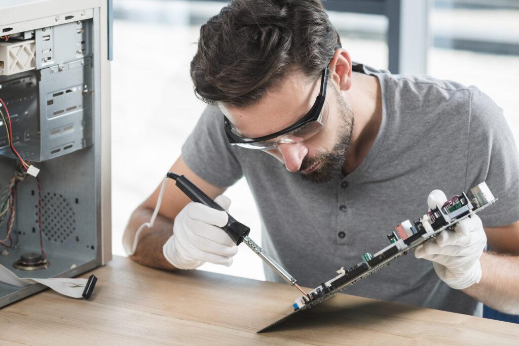young-man-soldering-computer-circuit-wooden-desk