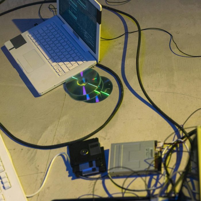 A modern and retro technology mix with laptops, floppy disks, and wires.